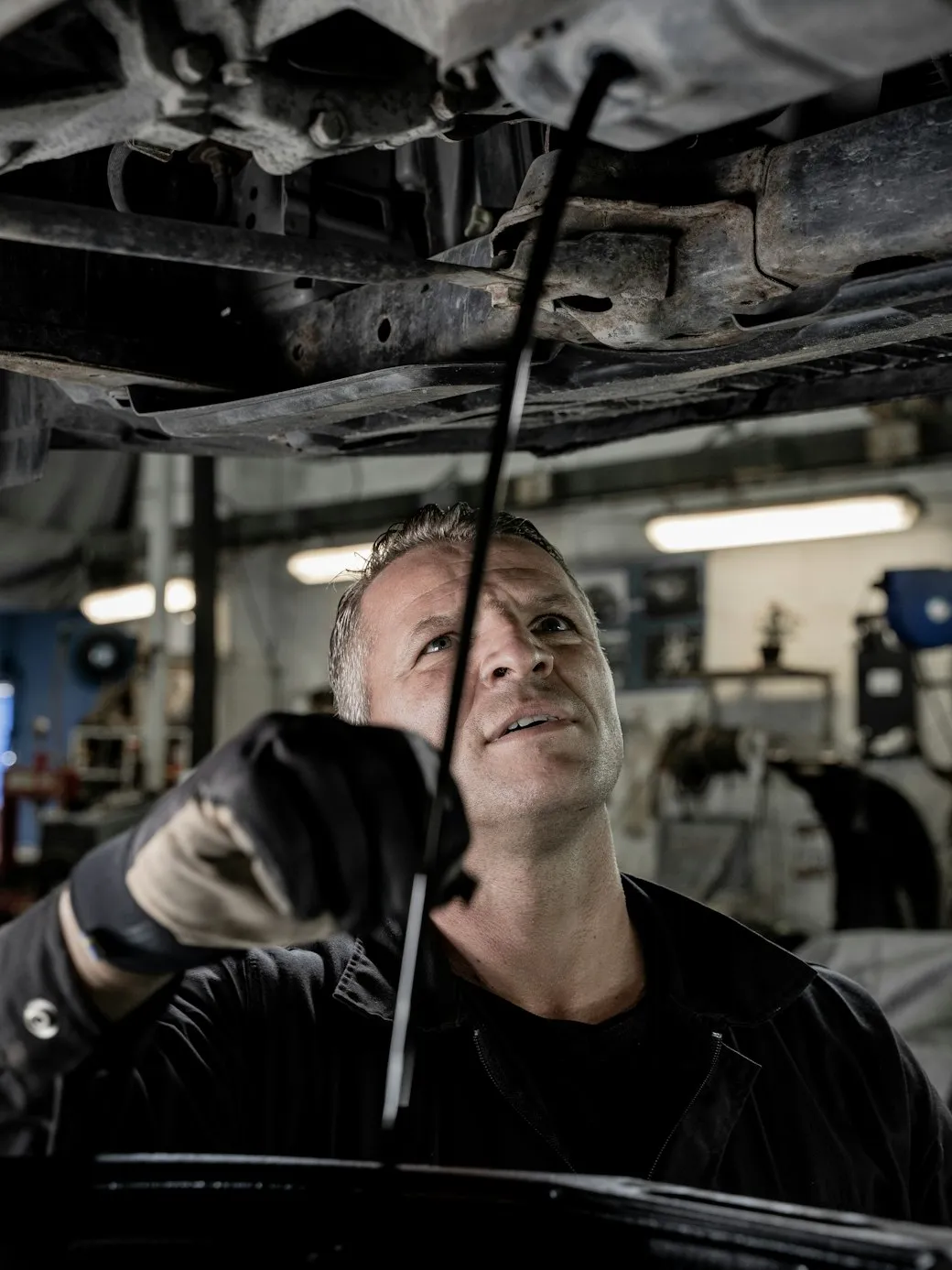 A technician working underneath a car on a workshop ramp